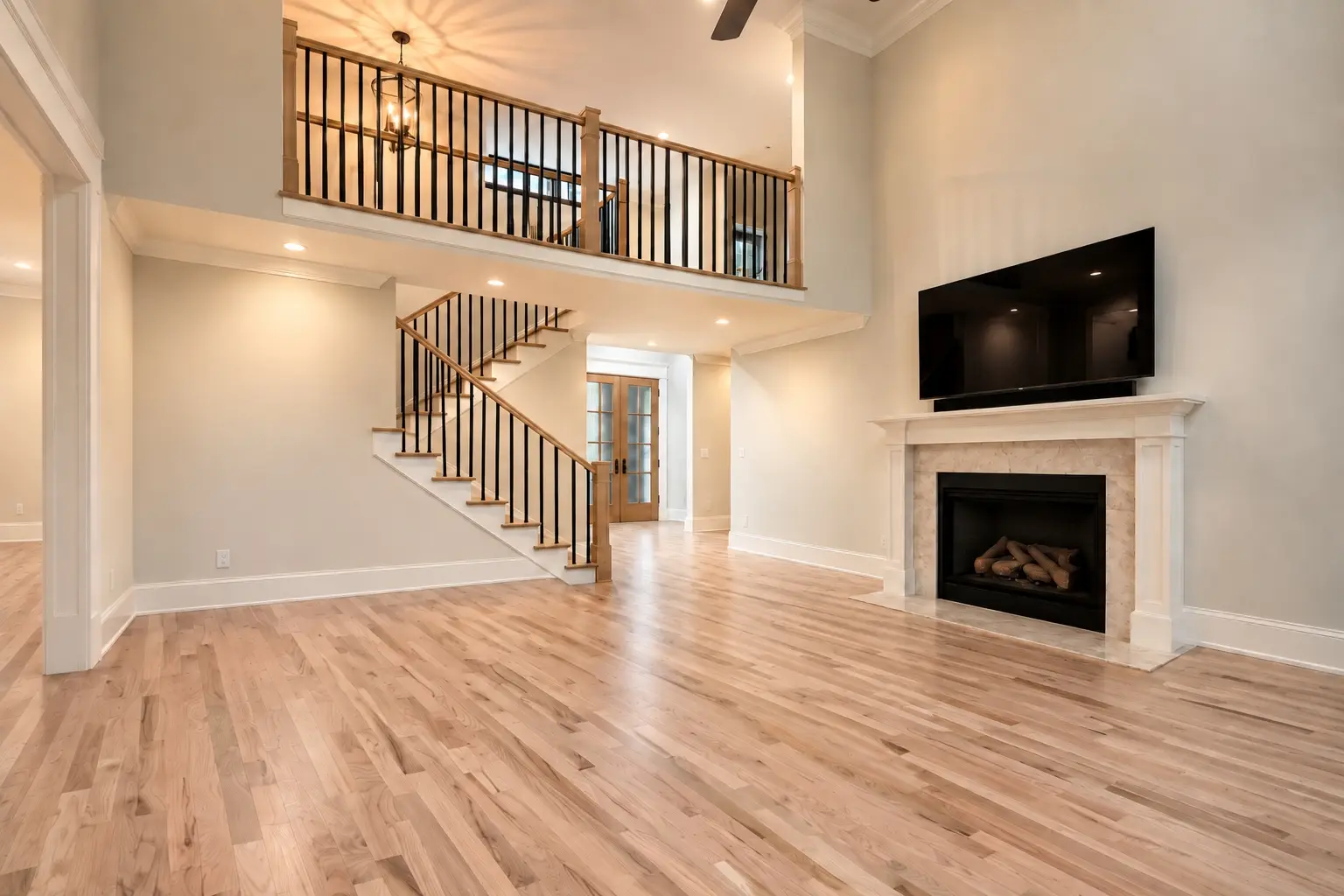 A two-story living room with newly finished natural oak hardwood floors, an open staircase, and a fireplace