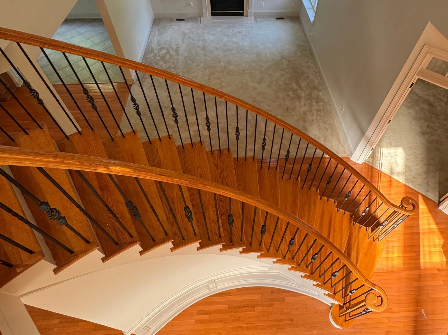 Before hardwood installation: Curved staircase and foyer, orange oak to dark brown