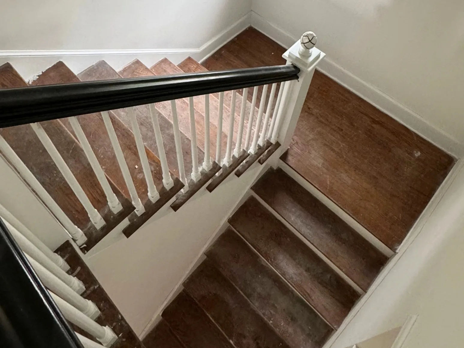 Before staircase refinishing: Staircase with black rail, deep brown treads