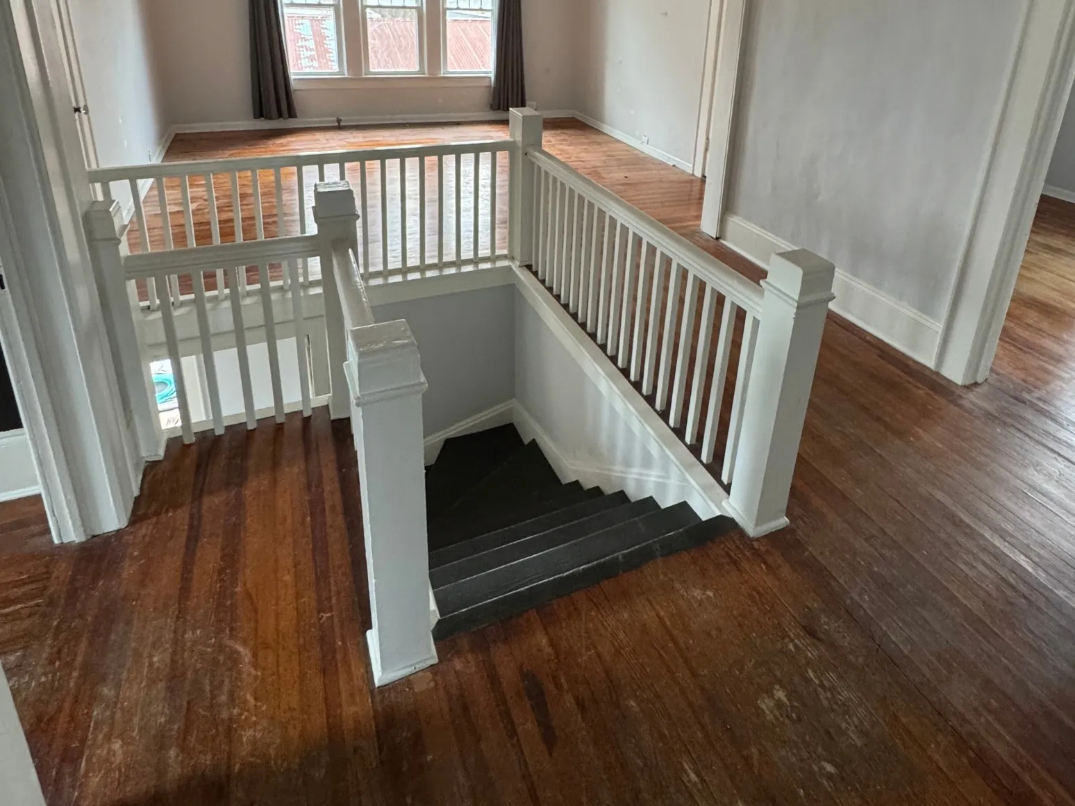 Before staircase refinishing: Worn floor and stairs, sanded to bare oak