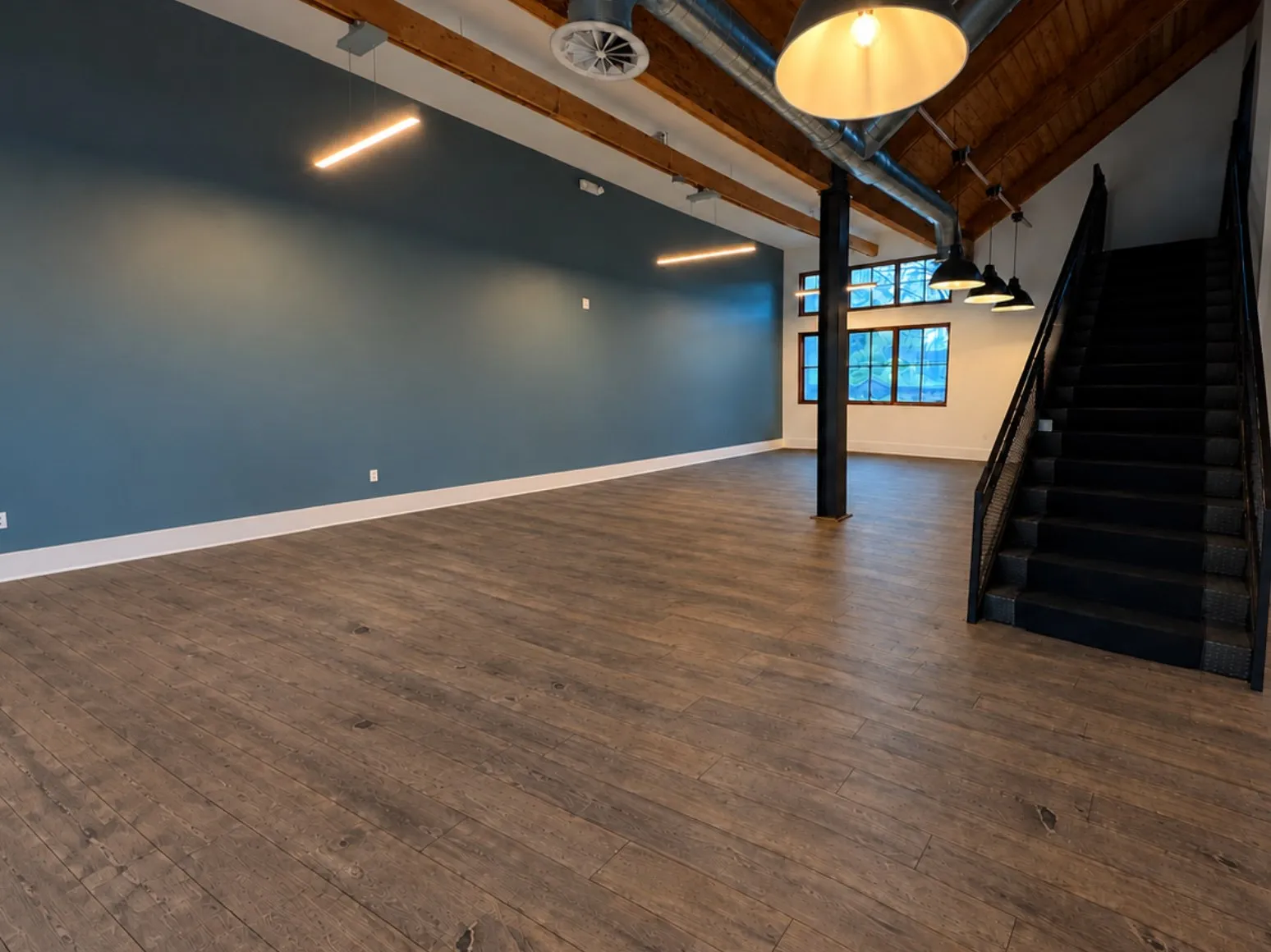 Before luxury vinyl plank installation: Open room, dark plank floor to light wood-look vinyl plank